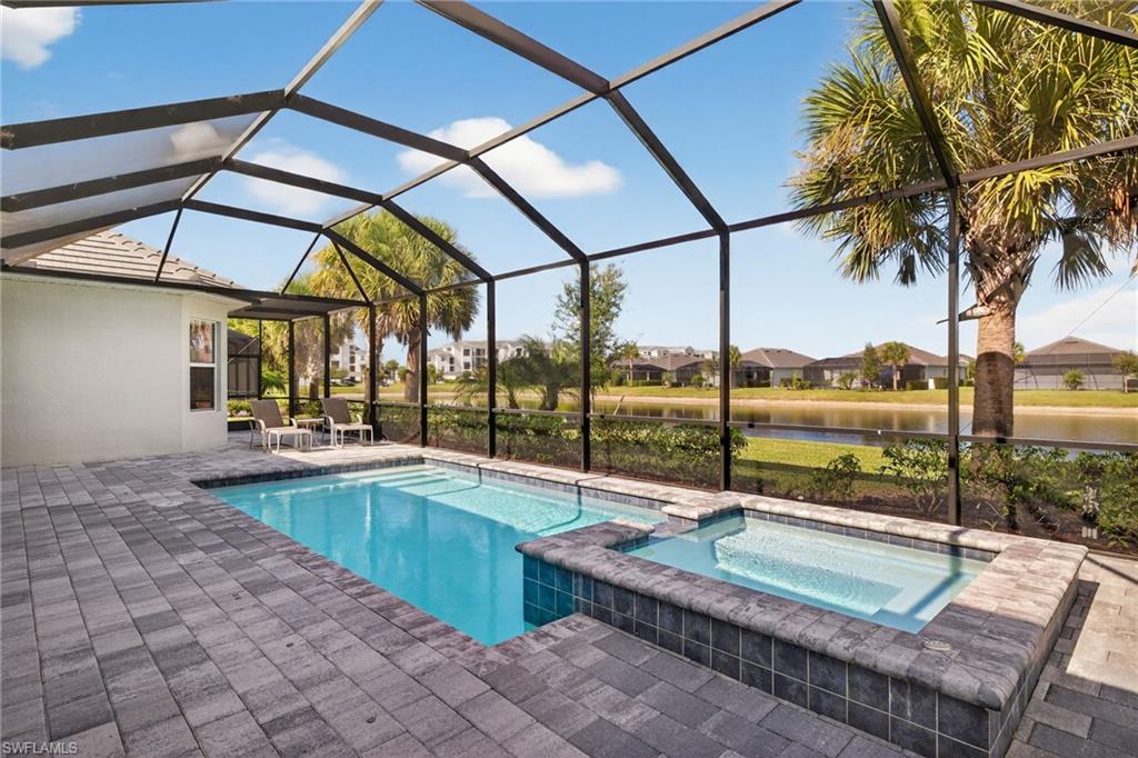 View of pool with a patio, a sunroom, a pool with connected hot tub, a residential view, and a water view