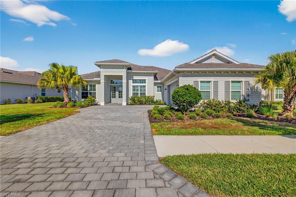 View of front of home featuring decorative driveway, a garage, a front lawn, and french doors