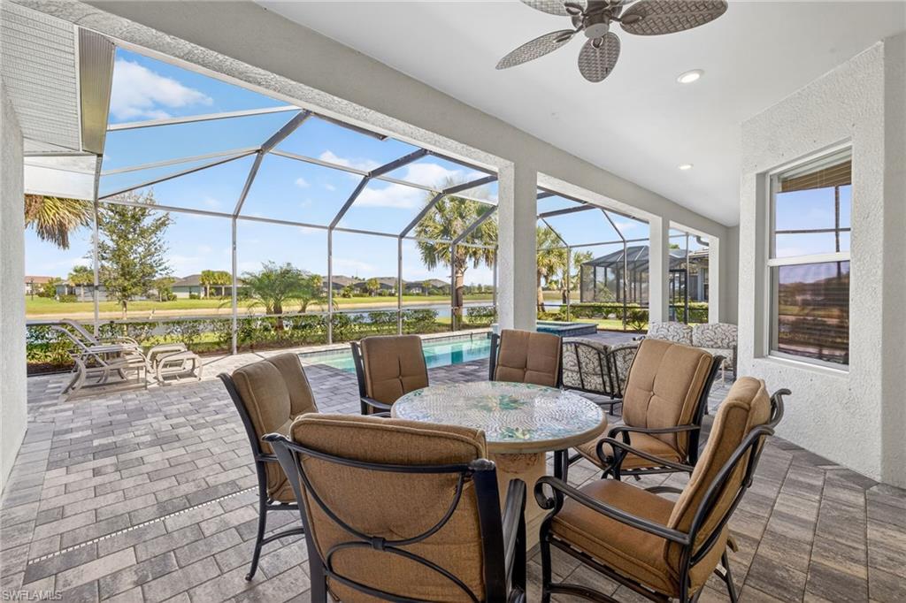 View of patio featuring a sunroom, outdoor dining area, an outdoor pool, glass enclosure, and ceiling fan