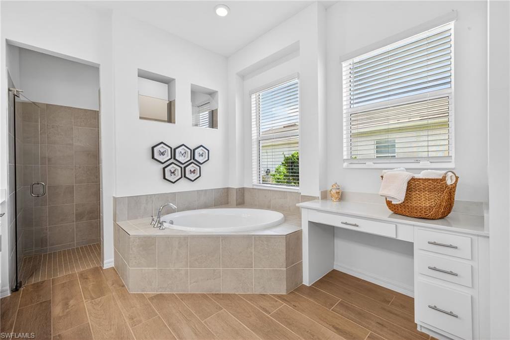 Bathroom featuring a shower stall, a bath, and wood finish floors