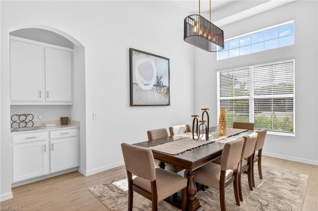 Dining area with light wood-style flooring and a towering ceiling