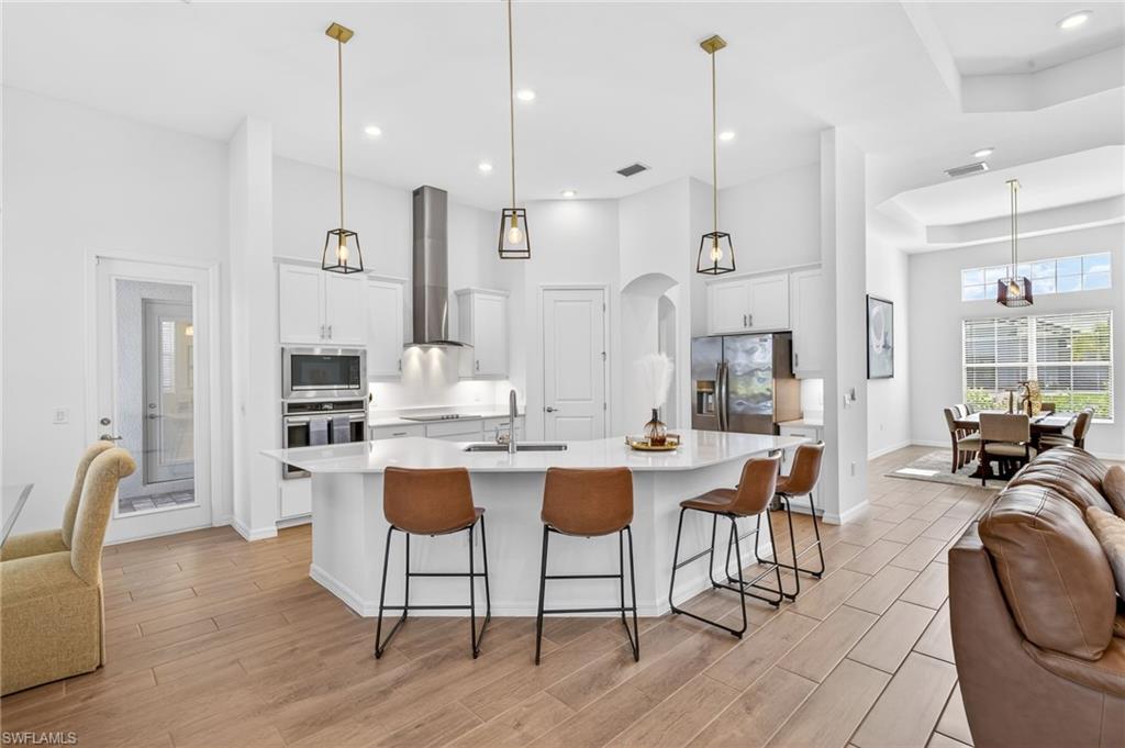 Kitchen featuring a high ceiling, a breakfast bar, open floor plan, decorative light fixtures, and appliances with stainless steel finishes