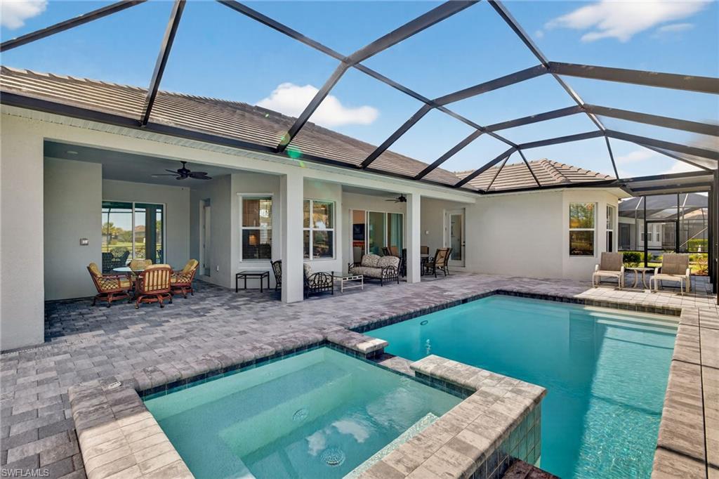 View of pool featuring a sunroom, a lanai, a pool with connected hot tub, outdoor dining space, and a patio