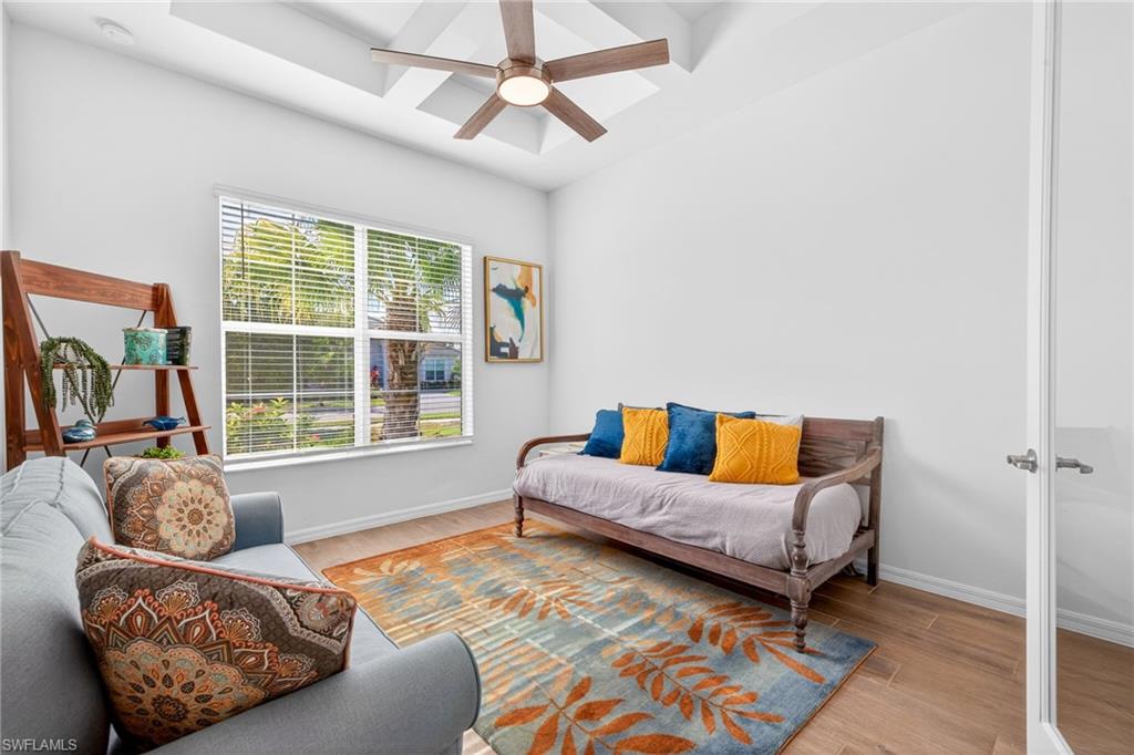 Sitting room with coffered ceiling, wood finished floors, beamed ceiling, and ceiling fan