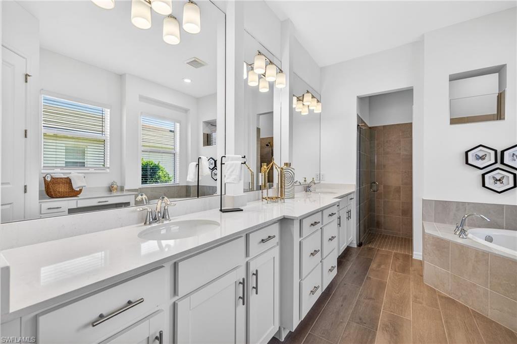 Bathroom with a bath, double vanity, a tile shower, and wood tiled floors
