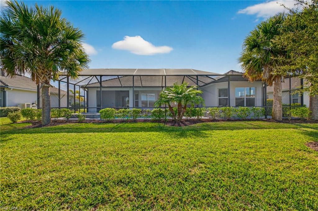 Back of property with a sunroom, glass enclosure, a lawn, and stucco siding