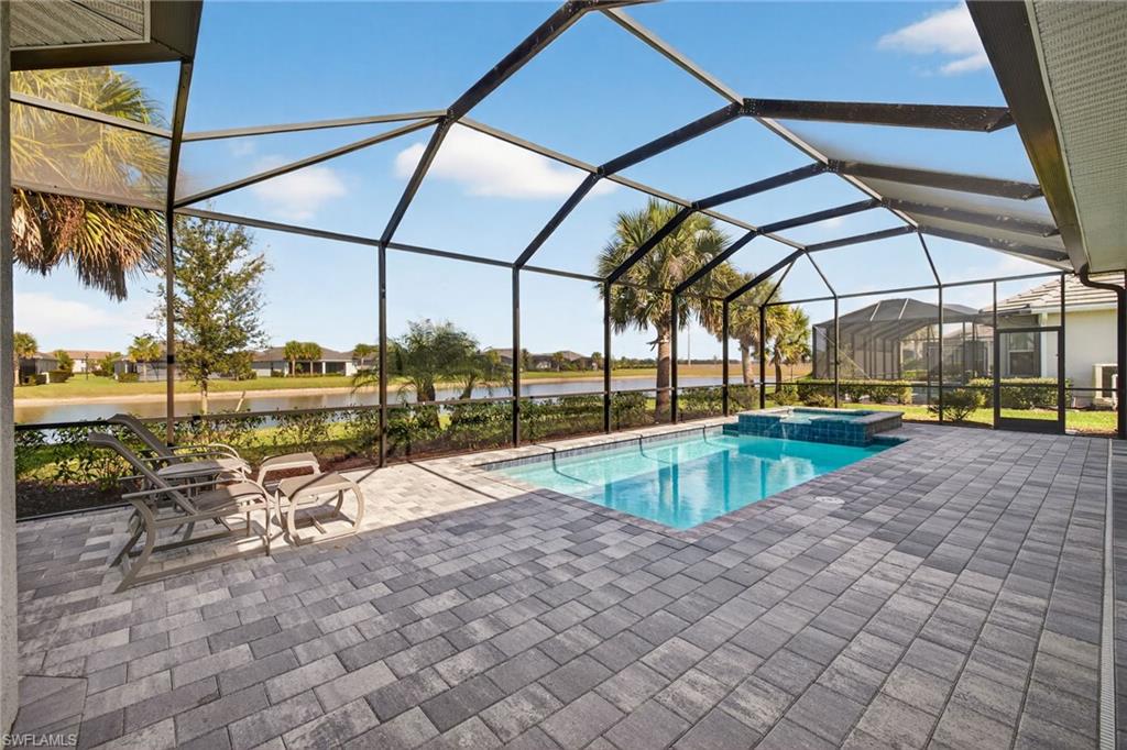 View of swimming pool featuring a sunroom, a patio, a pool with connected hot tub, a water view, and a lanai