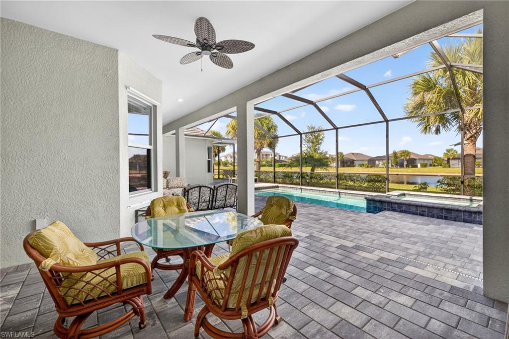 View of patio featuring a sunroom, outdoor dining area, a lanai, a pool with connected hot tub, and ceiling fan