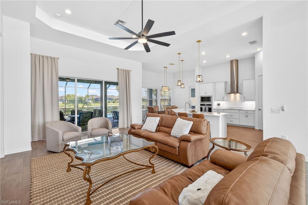 Living area featuring recessed lighting, a ceiling fan, a high ceiling, and a tray ceiling