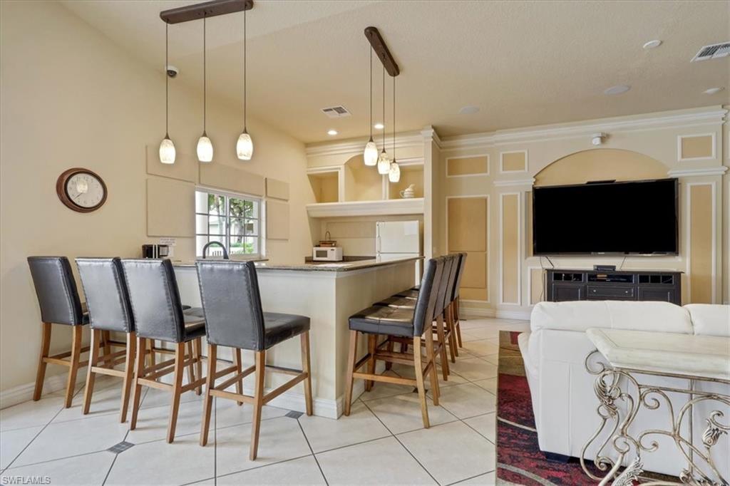 Kitchen area in clubhouse with pendant lighting, a breakfast bar, white appliances, a peninsula, and open shelves