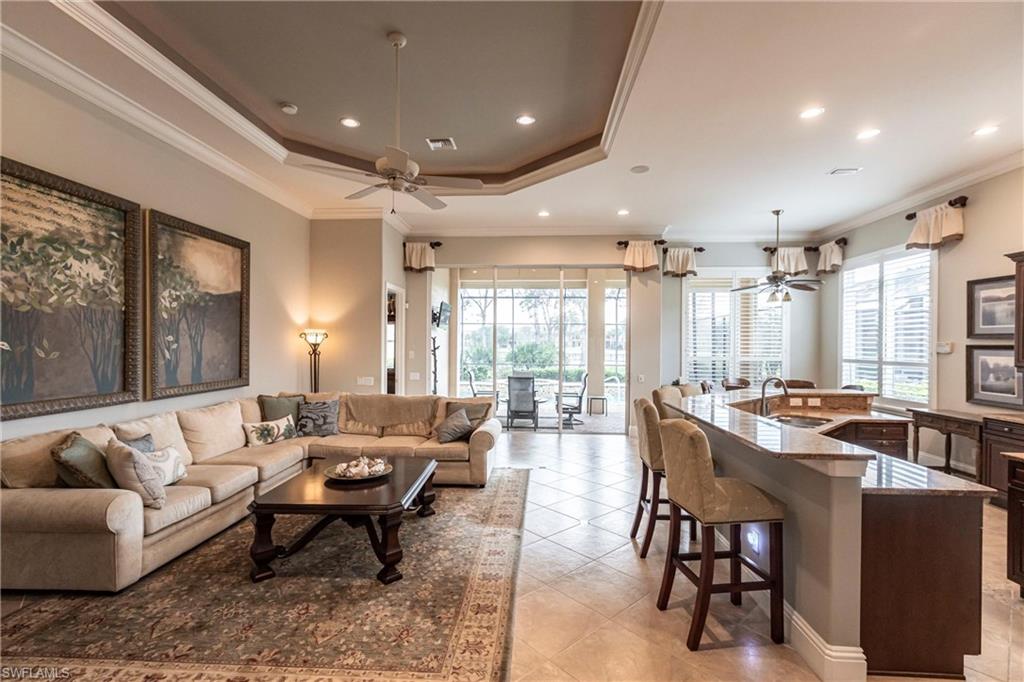 Living room featuring crown molding, ceiling fan, recessed lighting, light tile patterned floors, and a tray ceiling