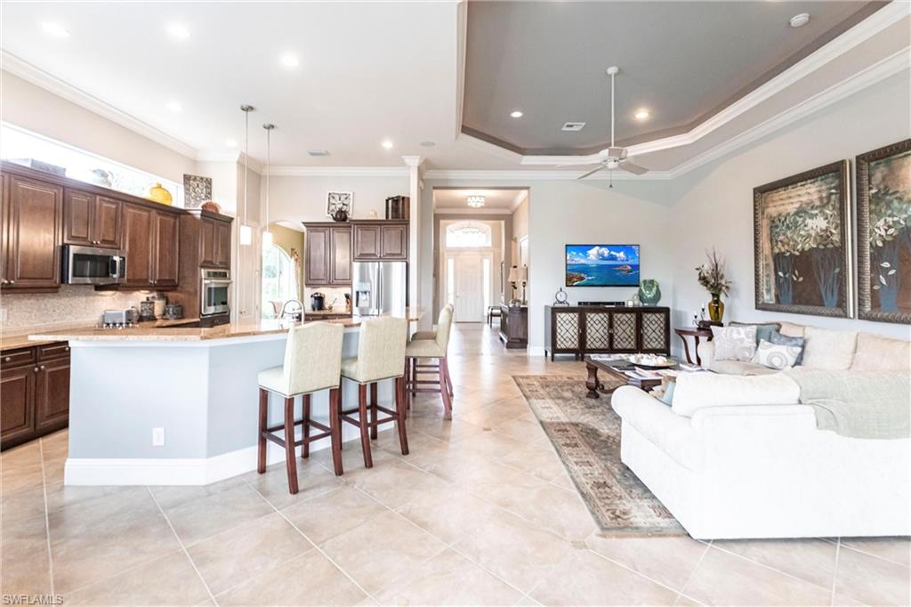 Living area with crown molding, a ceiling fan, arched walkways, recessed lighting, and light tile patterned flooring