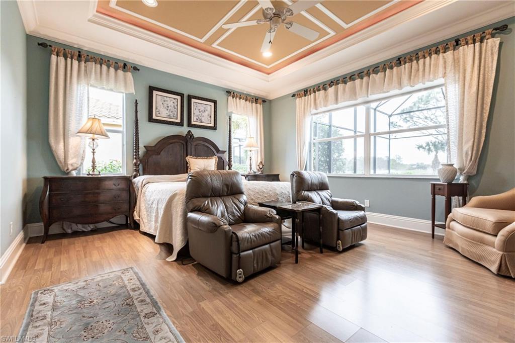 Bedroom featuring ornamental molding, a tray ceiling, light wood finished floors, and ceiling fan