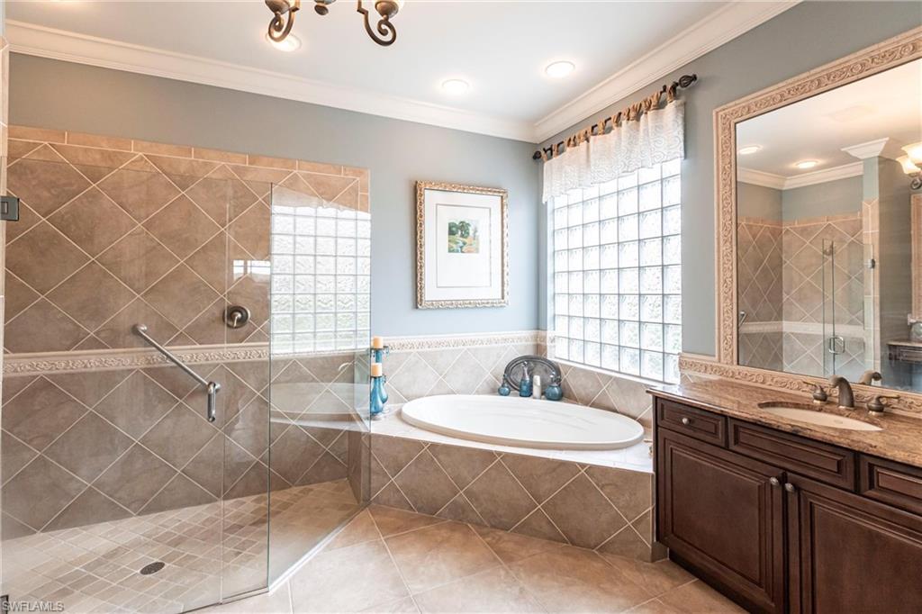 Full bath featuring a stall shower, healthy amount of natural light, a bath, crown molding, and vanity
