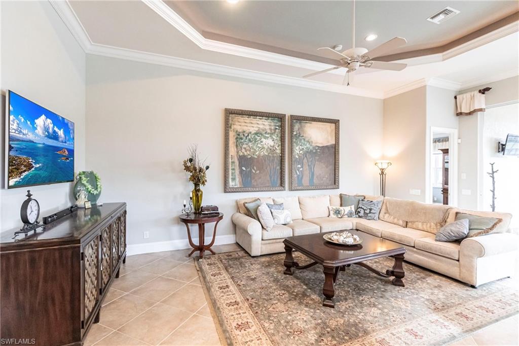 Living area featuring a tray ceiling, light tile patterned flooring, crown molding, a ceiling fan, and recessed lighting