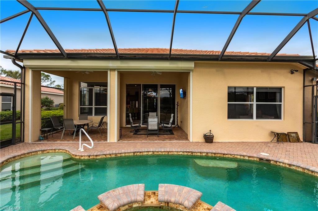 Back of property featuring a sunroom, a pool with connected hot tub, ceiling fan, and stucco siding