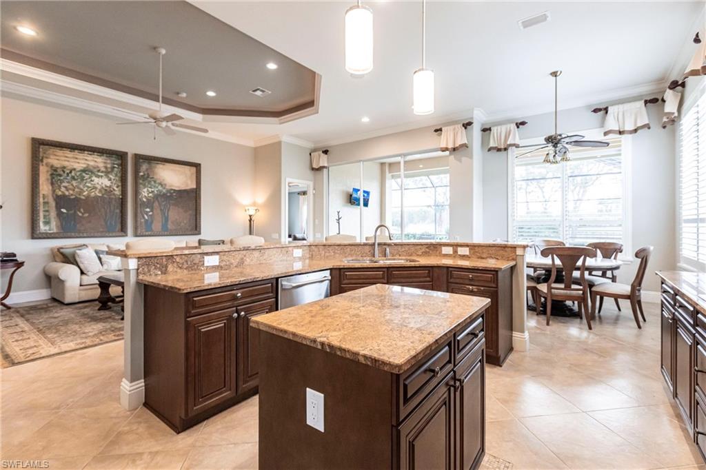 Kitchen featuring ceiling fan, dark brown cabinets, open floor plan, crown molding, and pendant lighting