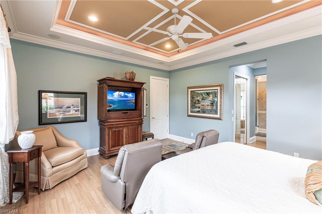 Bedroom with crown molding, light wood-style floors, ceiling fan, recessed lighting, and a tray ceiling
