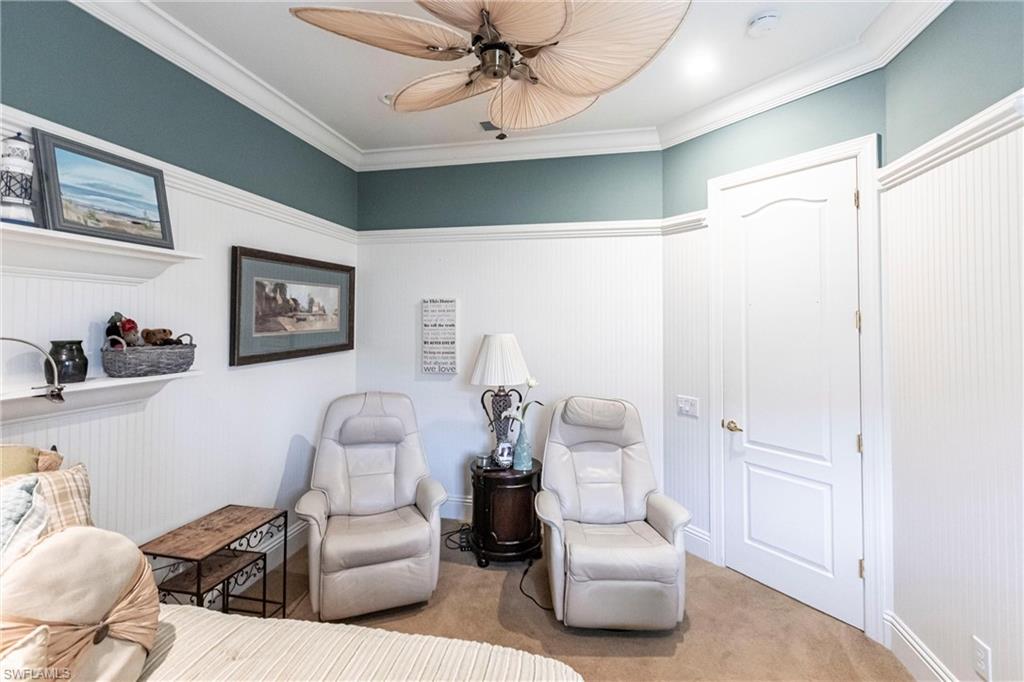 Sitting room featuring crown molding, carpet, wainscoting, and a ceiling fan