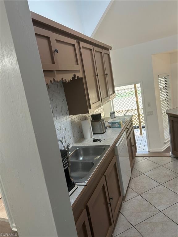 Kitchen featuring dishwasher, light tile patterned floors, sink, and tasteful backsplash