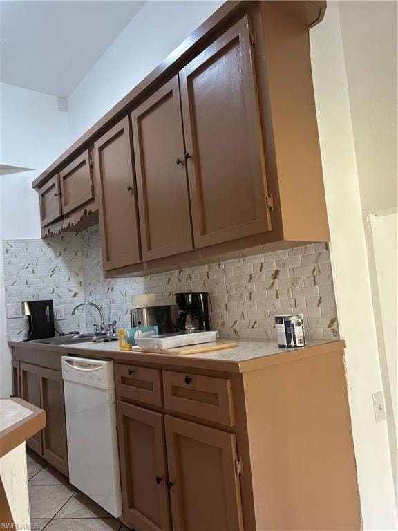 Kitchen featuring dishwasher, light tile patterned floors, tasteful backsplash, and sink