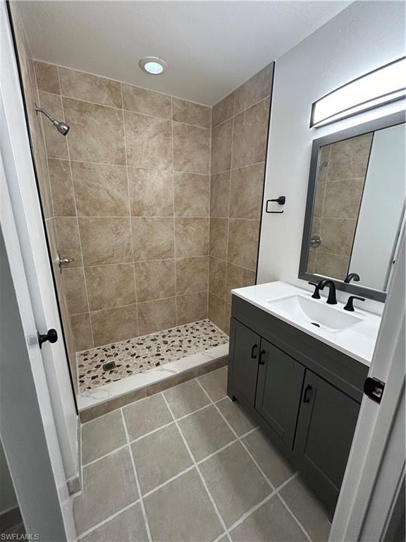 Bathroom featuring tiled shower, vanity, and tile patterned flooring