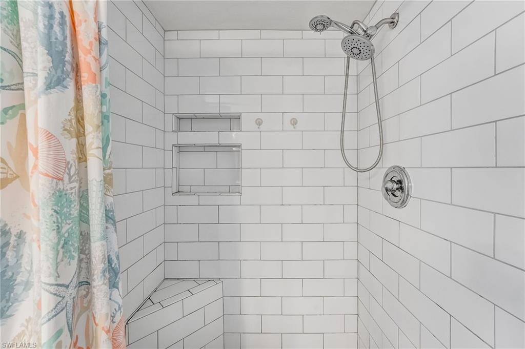 The primary bathroom features a walk-in shower with floor-to-ceiling subway tile.