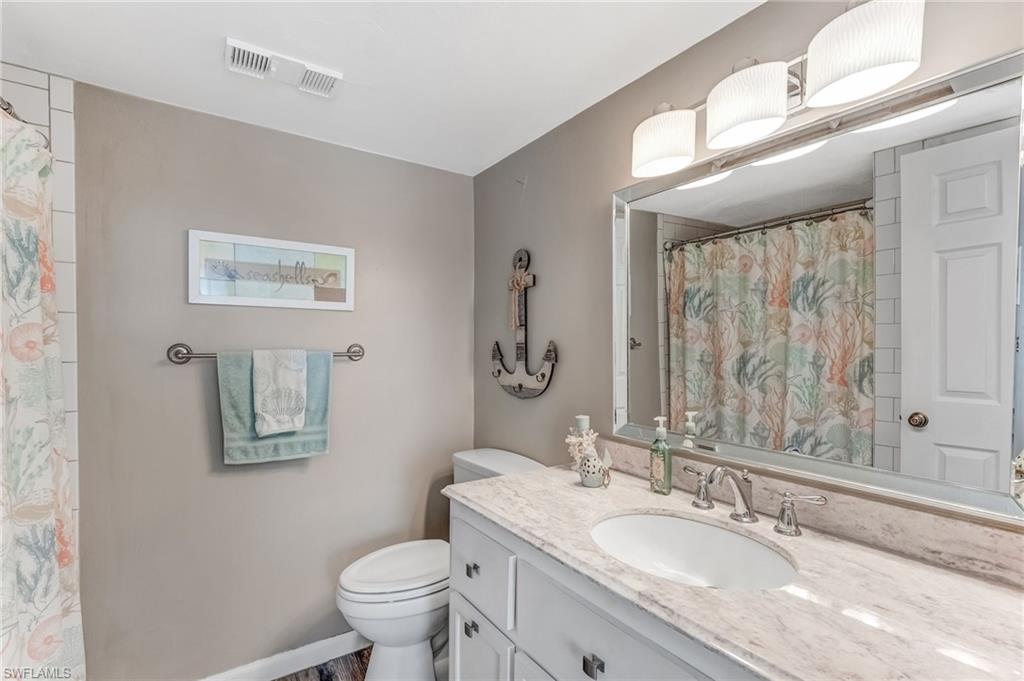Elegant bathroom with a sleek single vanity, pristine white cabinetry, a custom-designed mirror, and a spacious walk-in shower.