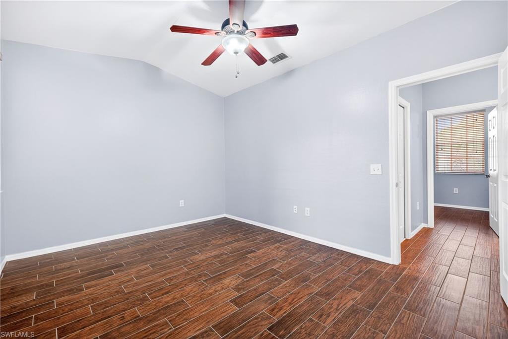 Unfurnished room with wood finish floors, vaulted ceiling, and a ceiling fan