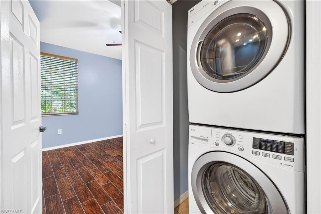 Laundry room with stacked washer and clothes dryer, wood finish floors, and a ceiling fan