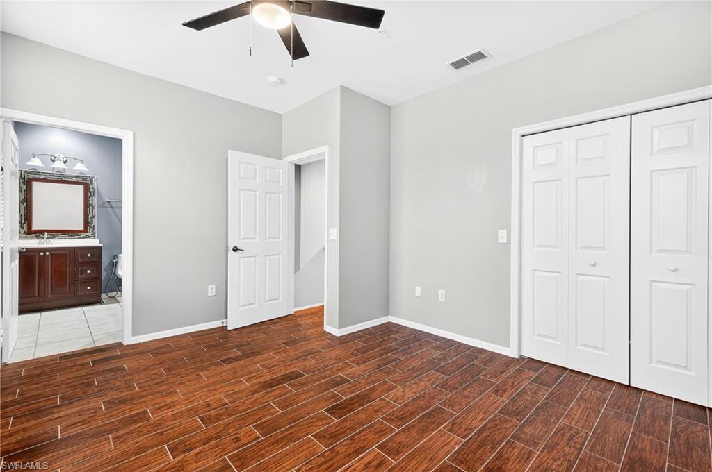Unfurnished bedroom with ceiling fan, wood tiled floors, a closet, and ensuite bathroom