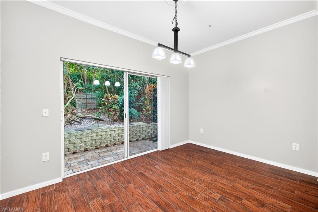 Unfurnished dining area with ornamental molding and dark wood-type flooring