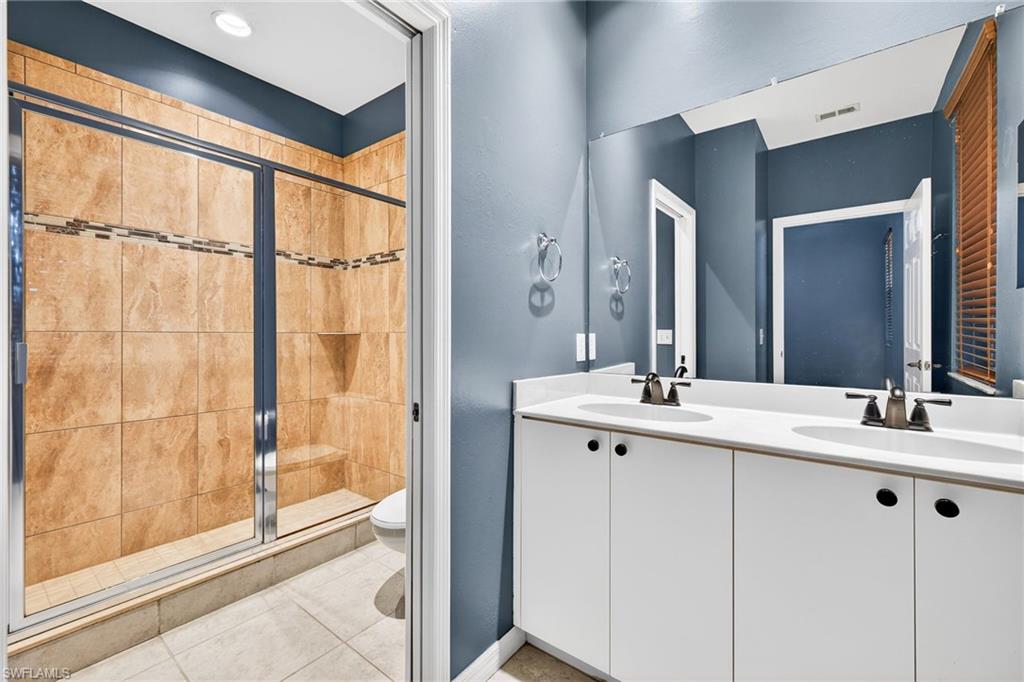 Bathroom with a stall shower, double vanity, and light tile patterned flooring