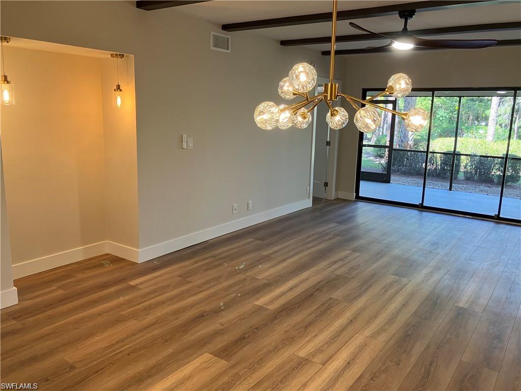 Unfurnished room with beamed ceiling, a chandelier, dark wood-style floors, and a ceiling fan