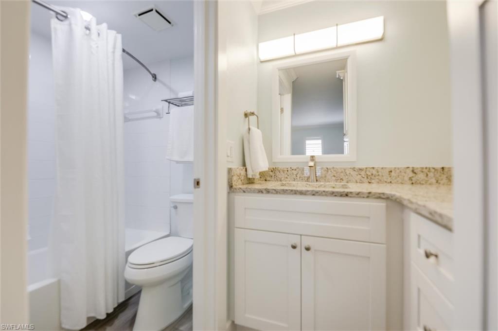 Full bath featuring shower / bath combo with shower curtain, vanity, and dark wood-style floors
