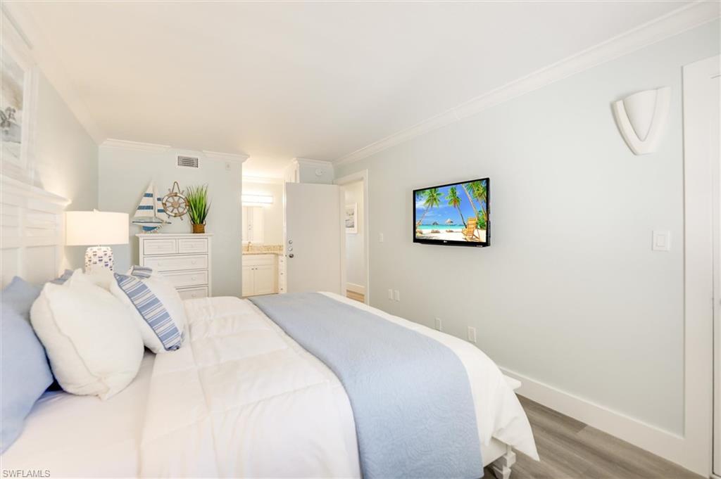 Bedroom featuring wood finished floors, crown molding, and ensuite bath