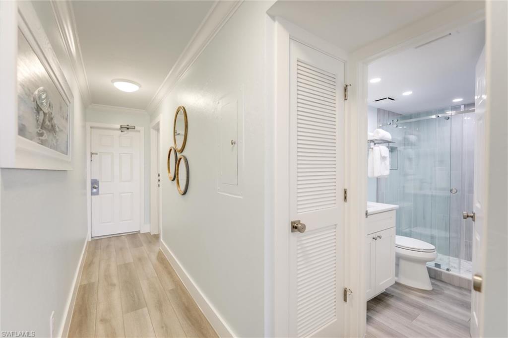 Hallway featuring light wood-style flooring, electric panel, and ornamental molding
