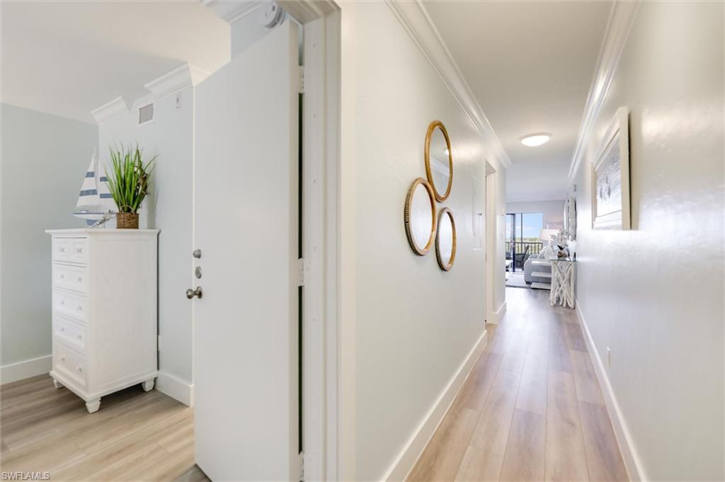 Hallway with ornamental molding and light wood finished floors