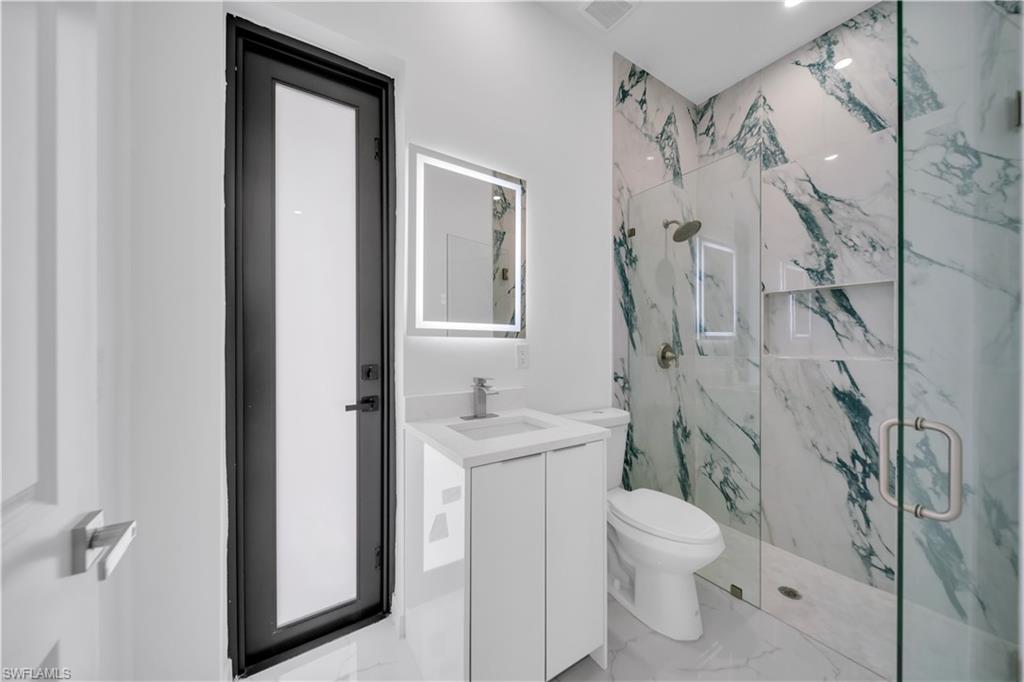 Bathroom with a marble finish shower, vanity, light marble finish flooring, and recessed lighting