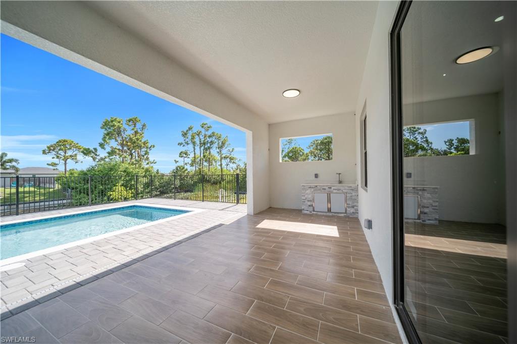 View of pool with patio surround, a fenced backyard, and exterior kitchen