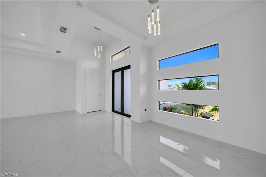 Spare room featuring a chandelier, a high ceiling, and light marble finish flooring