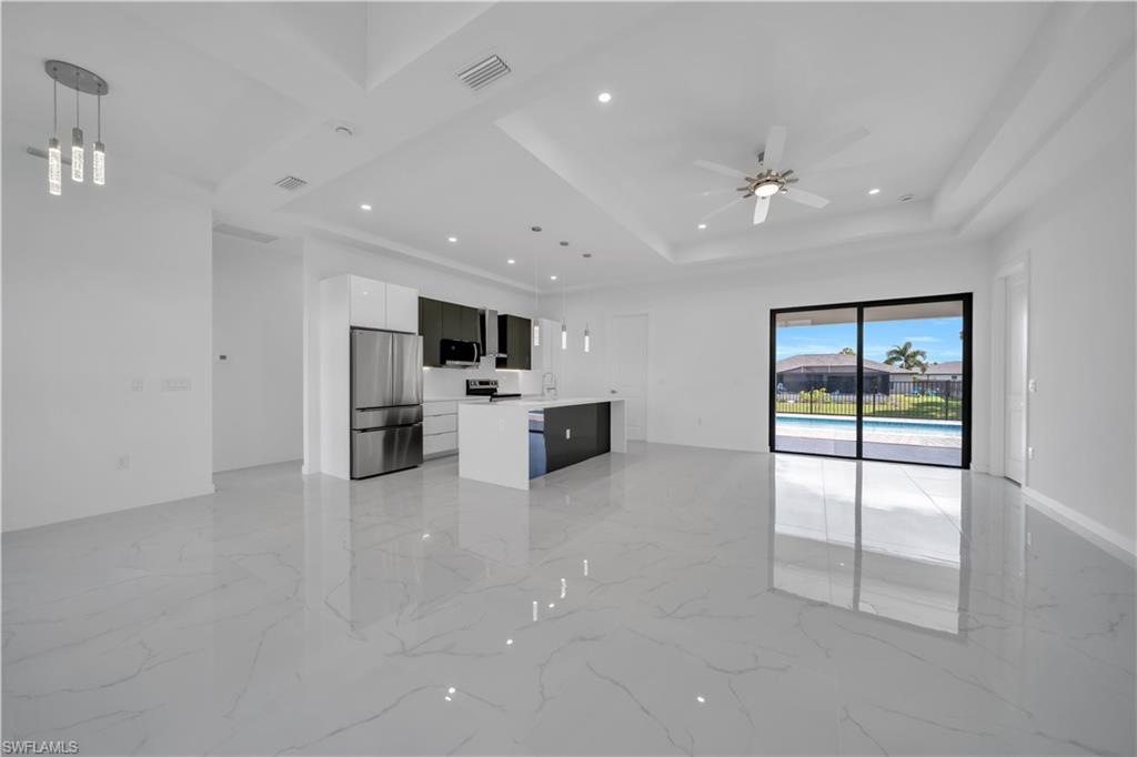 Unfurnished living room with a ceiling fan, recessed lighting, light marble finish flooring, and a raised ceiling