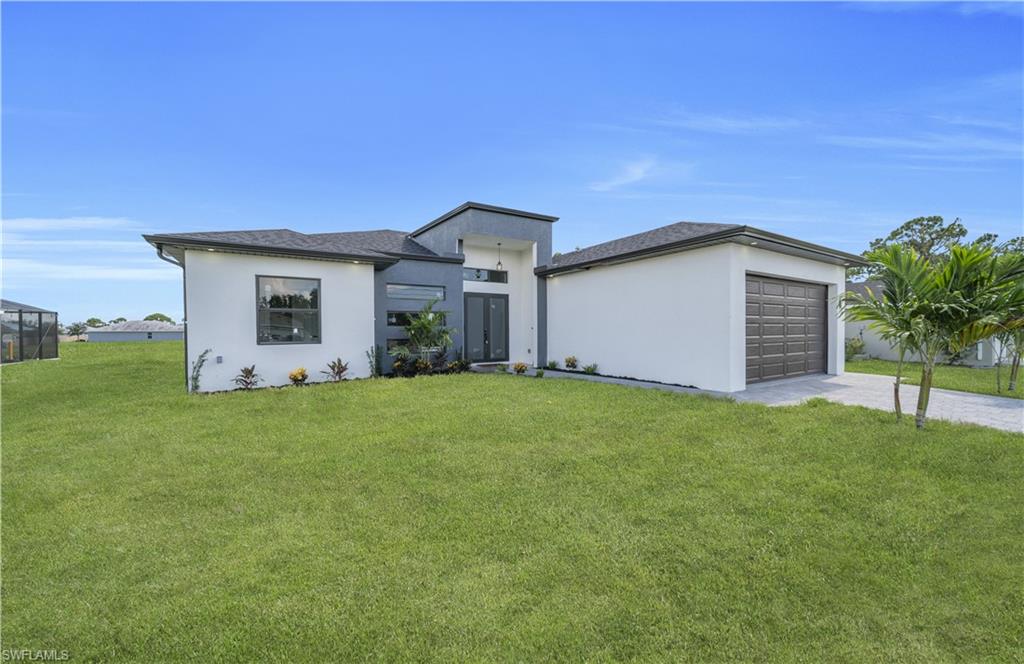 Contemporary exterior featuring a split-level roofline, stucco siding, an attached garage with a dark panel door, and a paver driveway