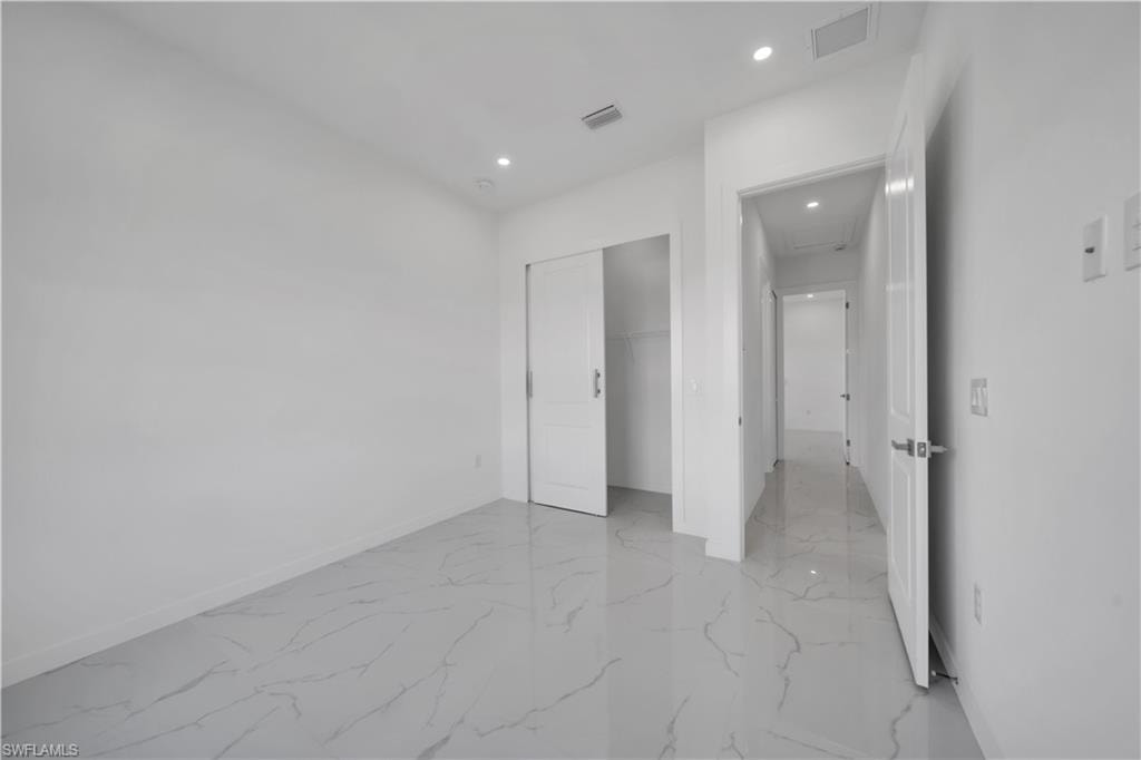 Unfurnished bedroom with recessed lighting, a closet, and light marble finish floors