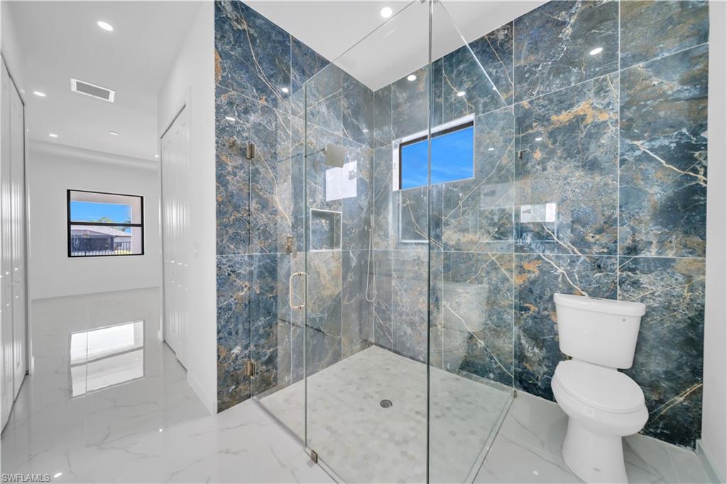Bathroom with a marble finish shower, recessed lighting, and marble tiled floors