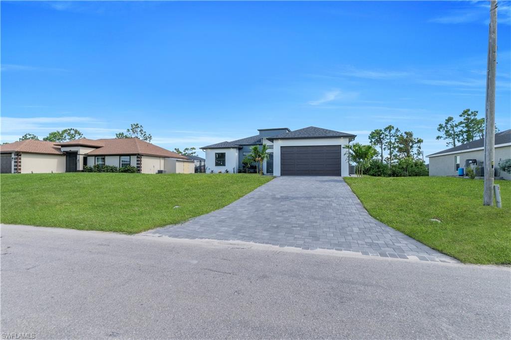 Contemporary exterior featuring a paver driveway, attached garage, and light-colored stucco finish