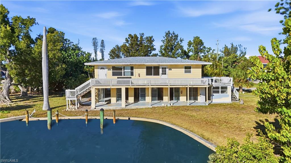 Rear view of property with stairway, a yard, a patio, a balcony, and a water view - Virtually Edited Image