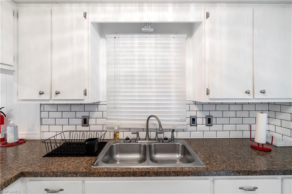 Kitchen featuring tasteful backsplash and white cabinetry