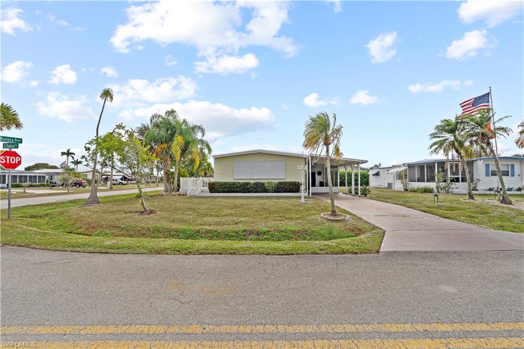 View of front of house with driveway, a front yard, and a carport