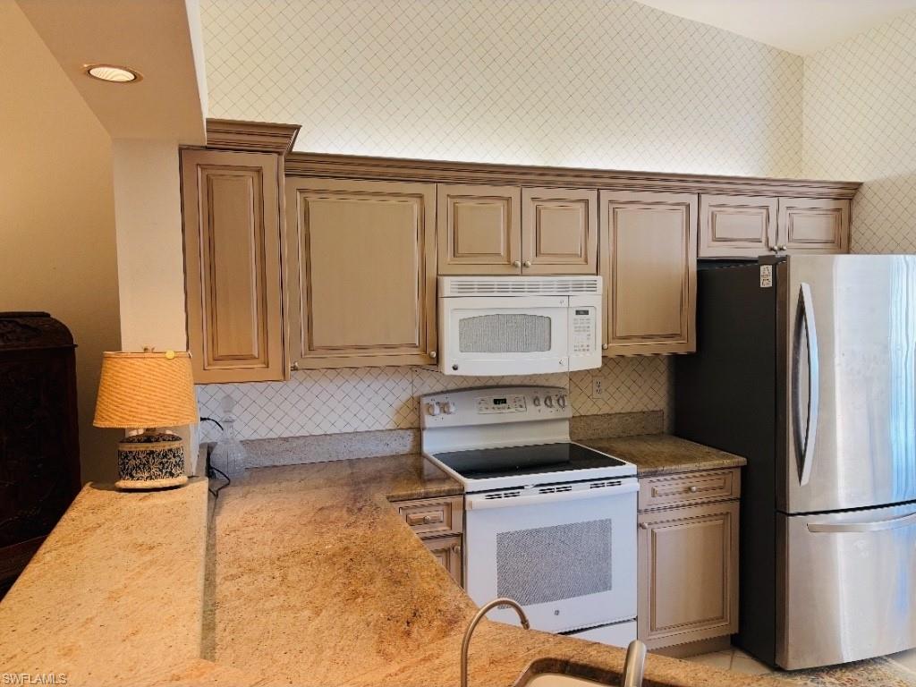 Kitchen with white appliances, light stone countertops, tasteful backsplash, and recessed lighting